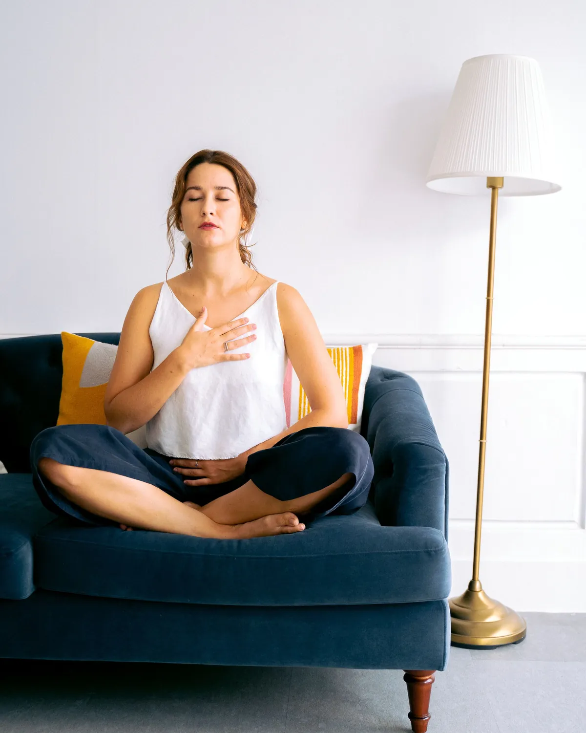 A woman sitting calmly on a navy sofa in a bright living room, breathing easy, for air quality testing in Falls Church, VA