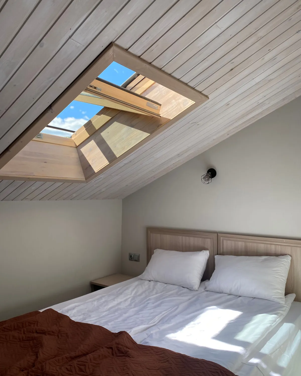 A bright, clean attic bedroom with a skylight and white bedding, for attic mold inspection in Falls Church, VA