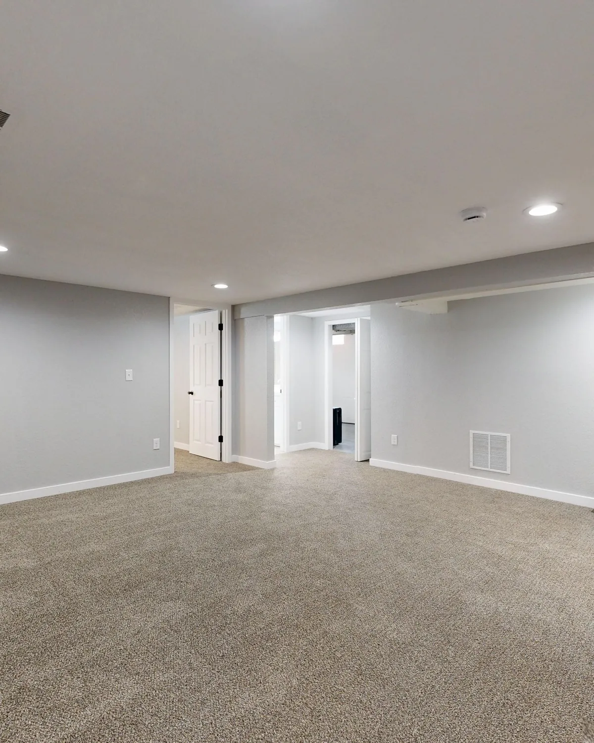 A clean, bright finished basement with fresh carpet and gray walls, for basement mold inspection in Falls Church, VA