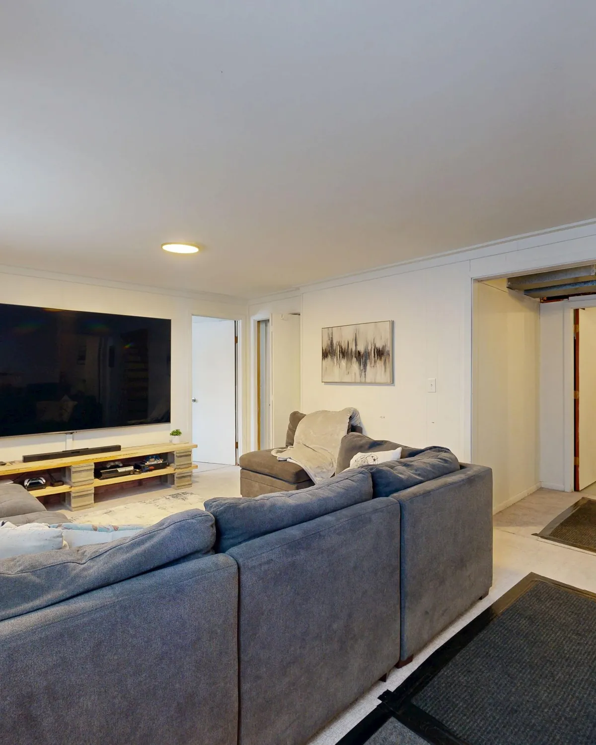 A clean basement family room with a gray sectional sofa and a wall-mounted TV, for basement mold removal in Falls Church, VA