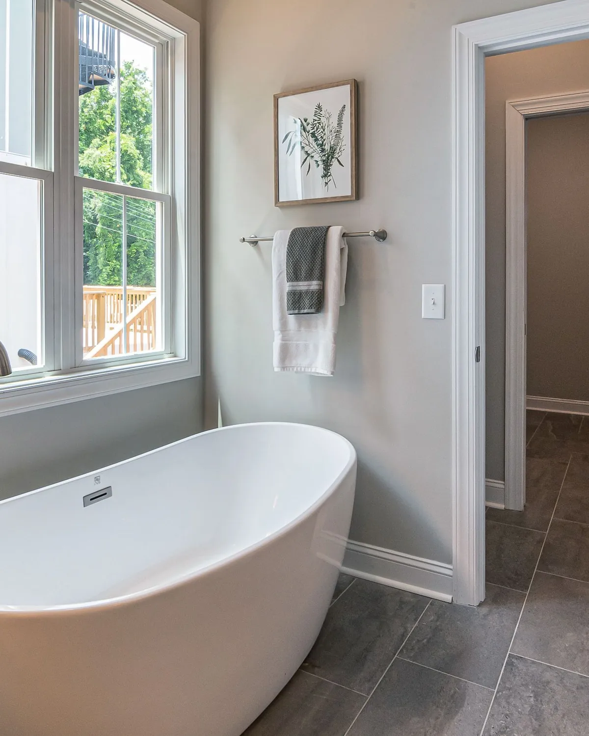 A clean, bright bathroom with a white freestanding tub beside a window, for bathroom mold removal in Falls Church, VA