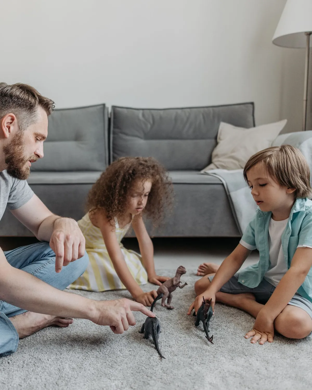 A father playing with two children on a clean gray living room carpet, for carpet mold removal in Falls Church, VA