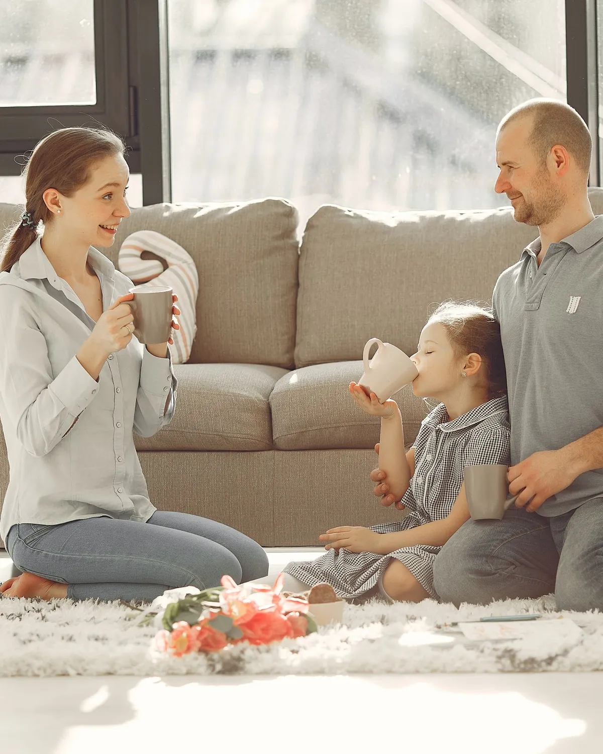 A family with two young children enjoying tea on a sunlit living room rug, for post-remediation clearance testing in Falls Church, VA