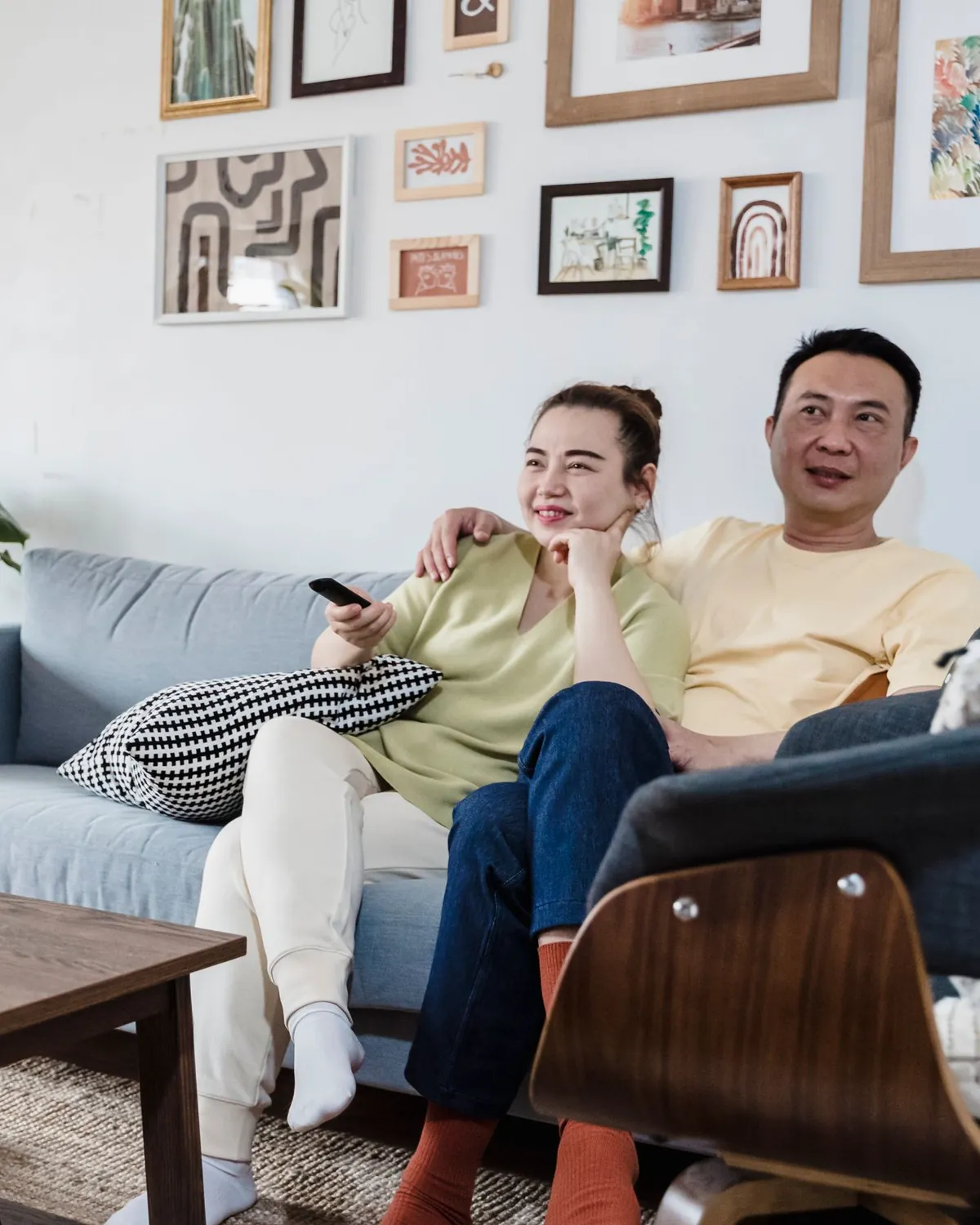 A couple relaxing on a sofa in front of a clean white wall with framed art, for wall mold remediation in Falls Church, VA