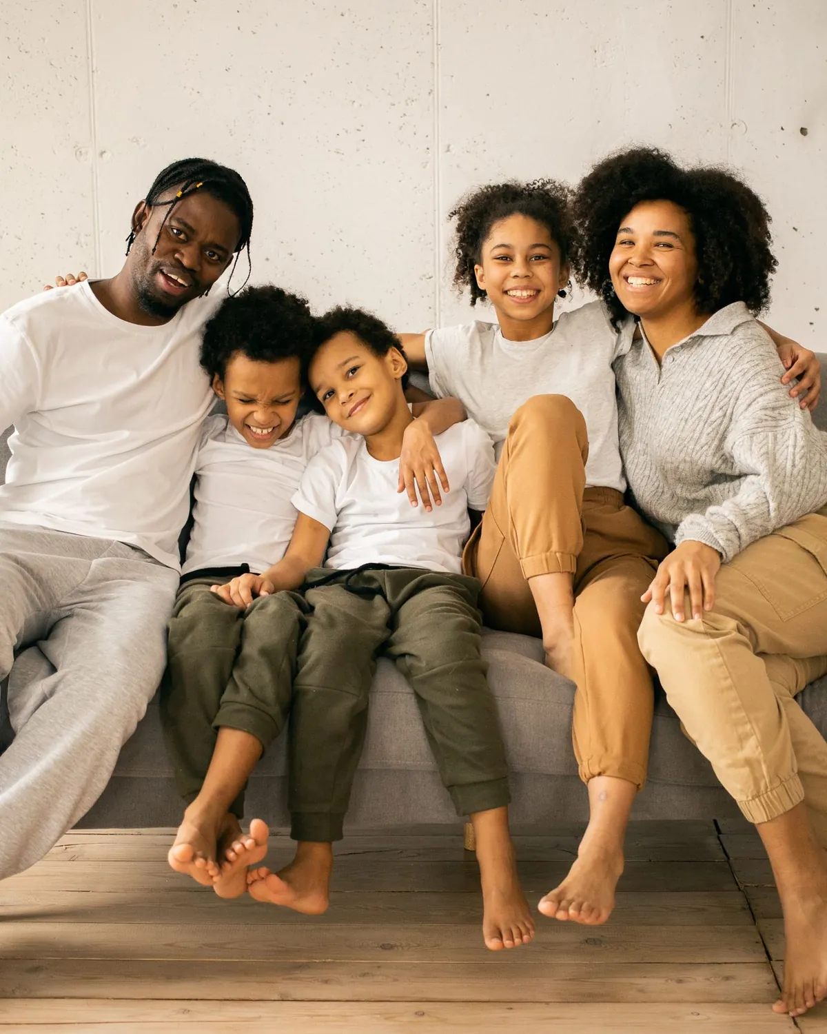 A smiling family of five sitting together on a sofa at home, for black mold removal in Falls Church, VA