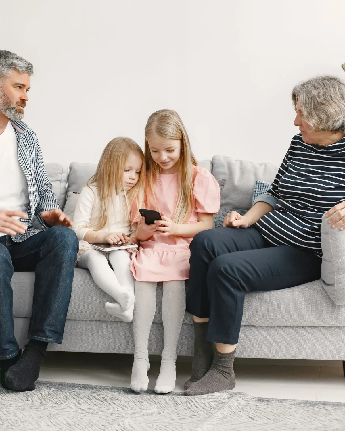 Grandparents and two young granddaughters on a living room sofa, for emergency mold treatment in Falls Church, VA