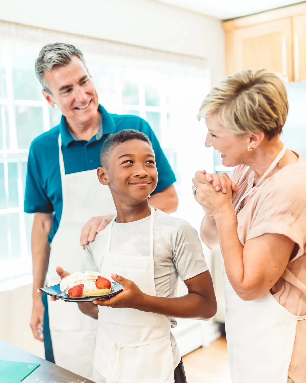 A grandfather, a boy and a grandmother smiling together in a bright kitchen, for water damage mold removal in Falls Church, VA