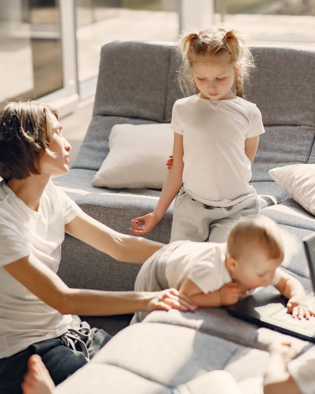 A mother and her children playing on a sofa in a sunlit living room, for ceiling mold removal in Falls Church, VA
