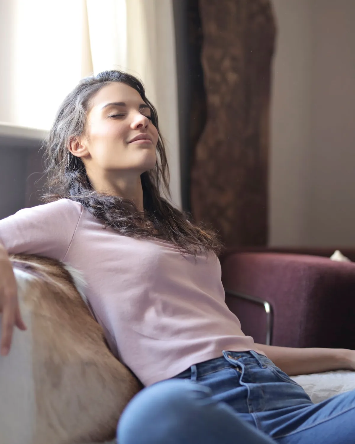 A woman relaxing on a sofa with her eyes closed in a bright room, for HVAC mold removal in Falls Church, VA